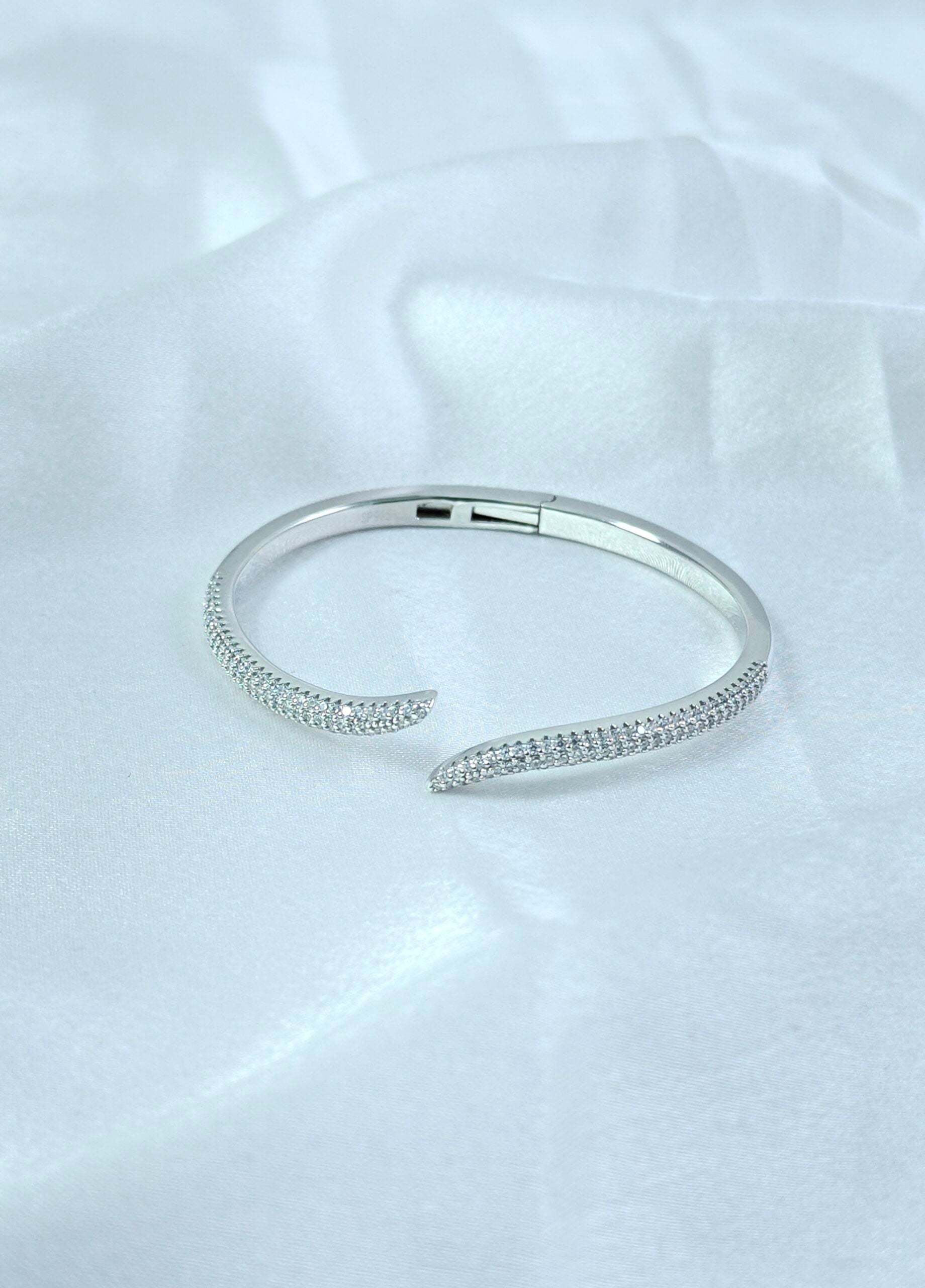 Silver bracelet on a white satin background